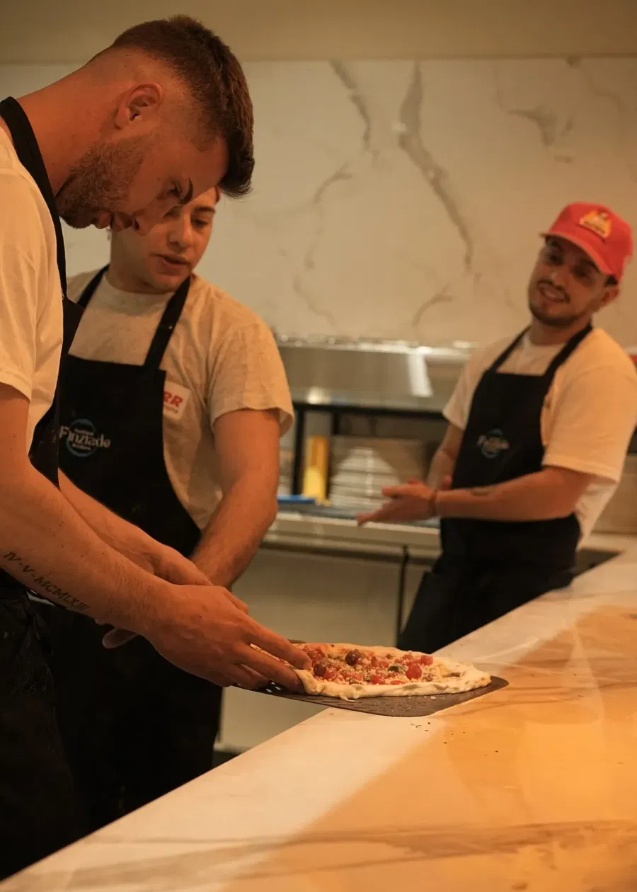 I pizzaioli sistemano una pizza sulla pala