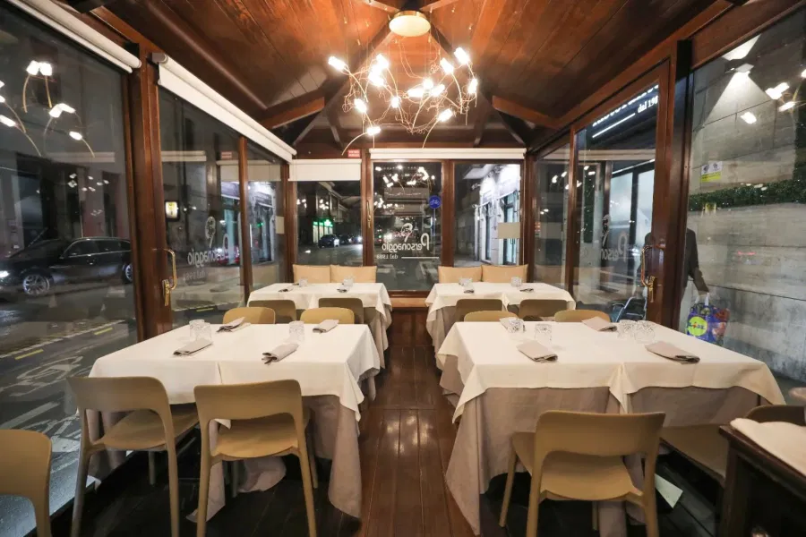 La veranda con il lampadario e le tavole apparecchiate di bianco