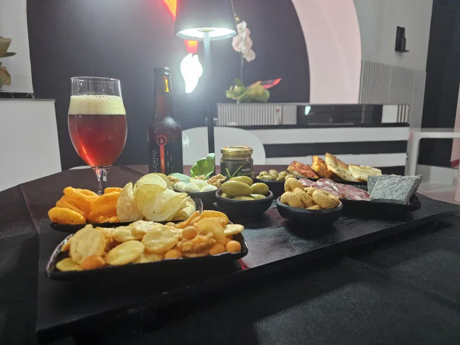 Tagliere da aperitivo con stuzzichini, olive e una birra ambrata