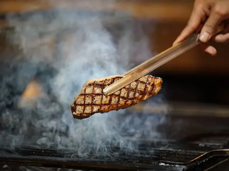 Bistecca presa con la pinza sopra la brace