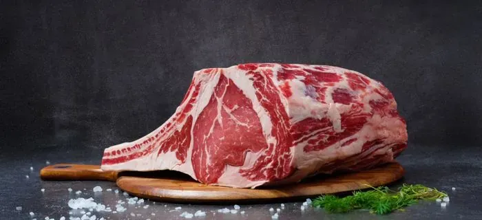 Taglio di carne con l'osso su un tagliere scuro