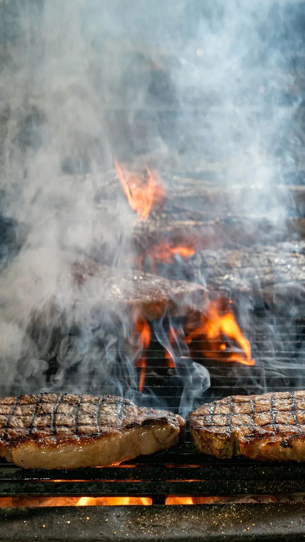 Bistecche sulla griglia tra il fumo e le fiamme