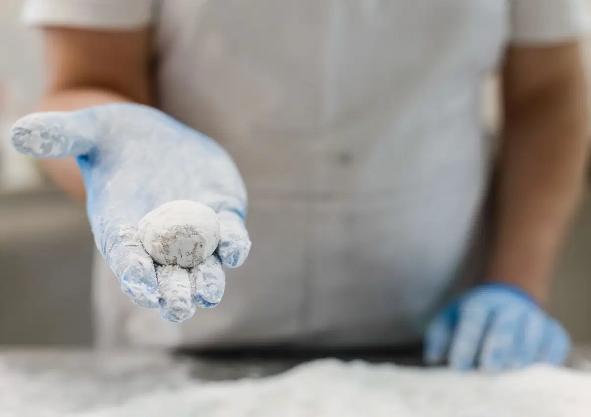 Una pasta di mandorla coperta di zucchero a velo, sul palmo della mano