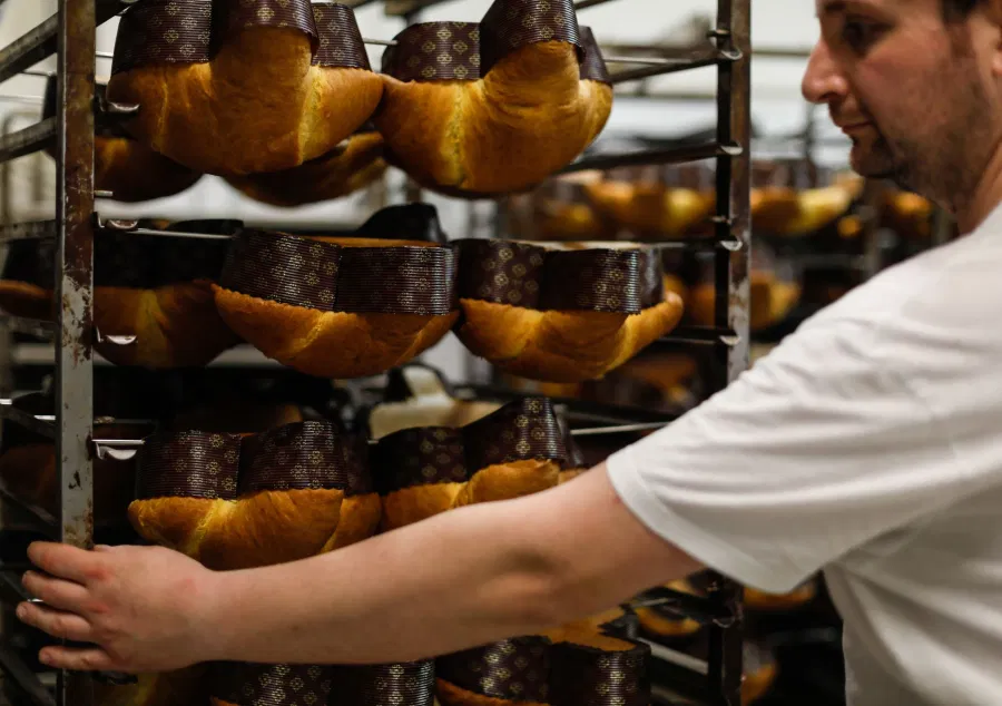 Un pasticcere sistema i panettoni appena sfornati sul carrello