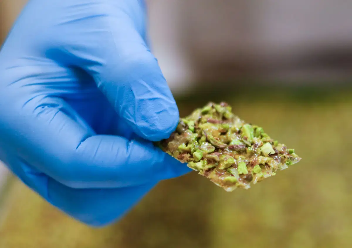Un pezzo di croccante al pistacchio tenuto fra le dita