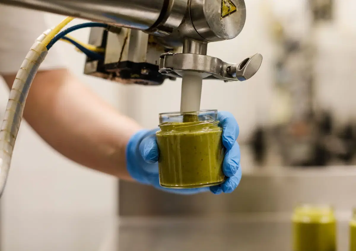 Un vasetto riempito di crema di pistacchio dalla dosatrice